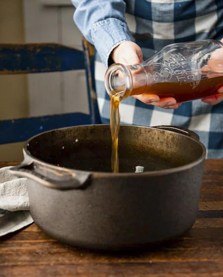 Pouring broth into a Dutch oven.