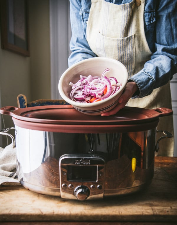 Adding red onions and carrots to a slow cooker