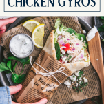 Hands picking up a plate of crock pot chicken gyros with text title box at top