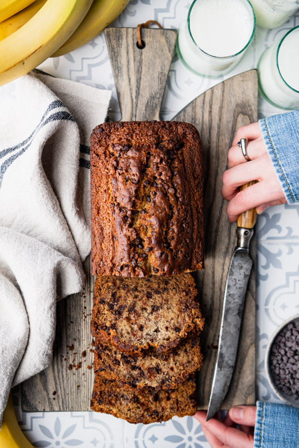 Hands holding a sliced loaf of chocolate chip banana bread