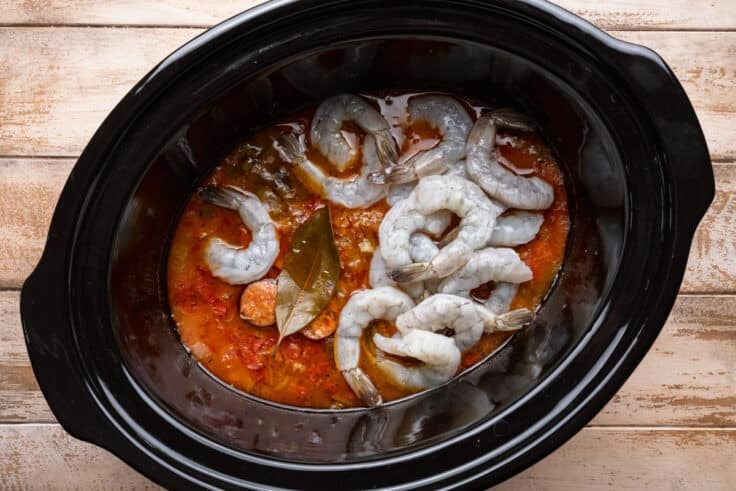 Adding raw shrimp to the Crock Pot.
