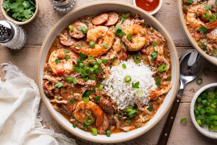 Horizontal overhead shot of a bowl of slow cooker gumbo with chicken, sausage, and shrimp and rice on top.