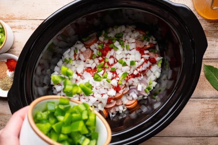 Placing diced green bell pepper in the Crock Pot.