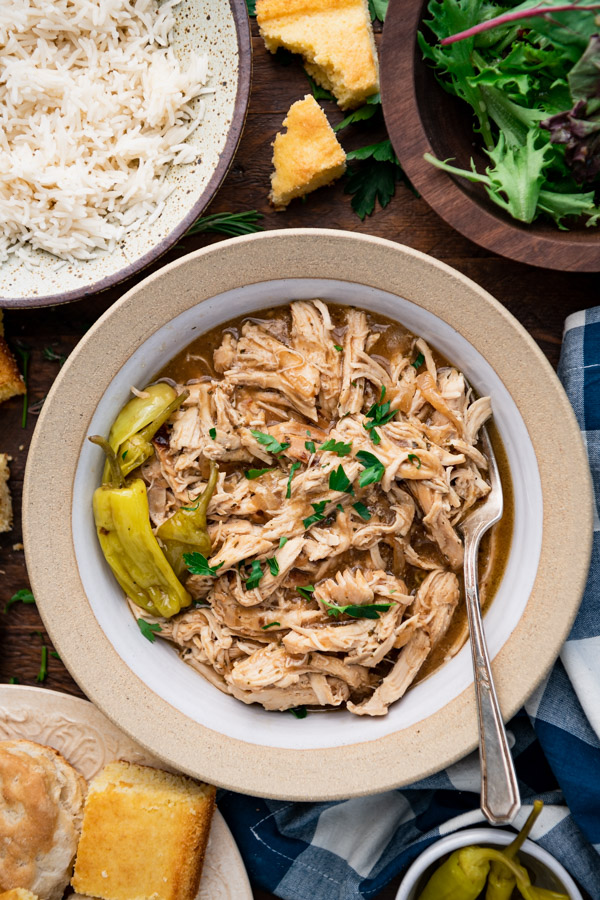 Close overhead image of a bowl of crock pot mississippi chicken on a wooden table