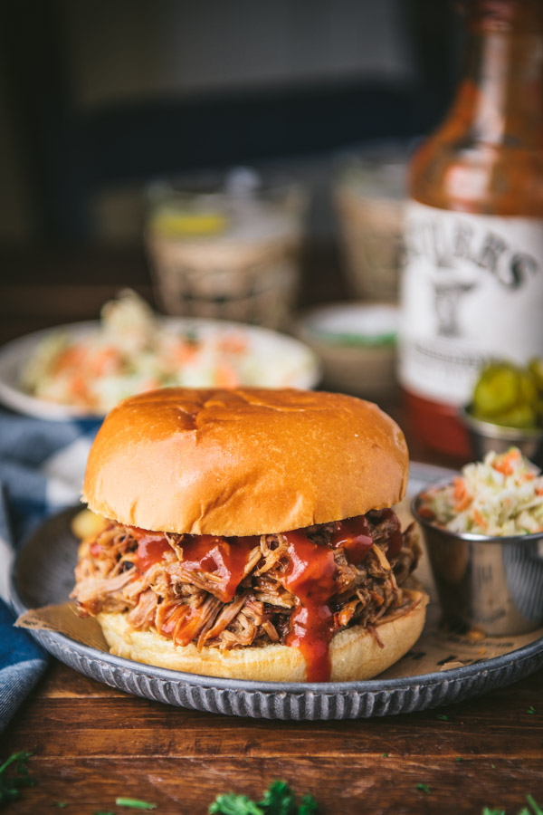 Close up side shot of pulled pork sandwich on a plate with a side of coleslaw