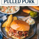 Plate of crock pot pulled pork sandwich on a dinner table with text title box at top