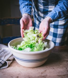 Adding iceberg lettuce to a large bowl