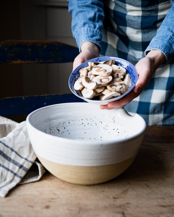 Adding mushrooms to a large bowl