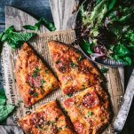 Overhead shot of pepperoni flatbread pizza on a cutting board with a side salad
