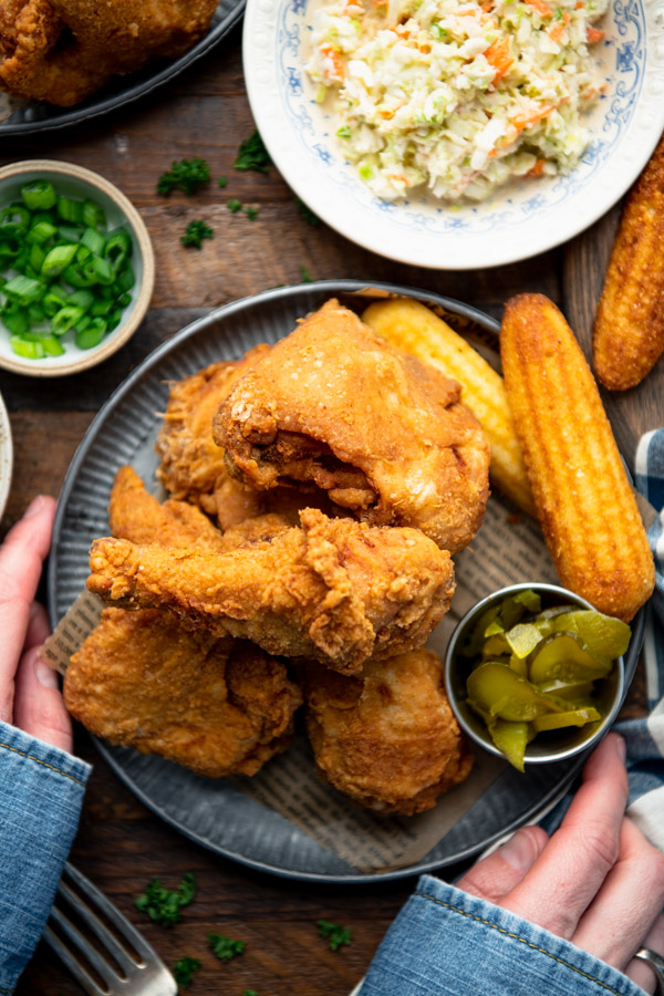 Overhead shot of hands holding a plate of the best fried chicken recipe