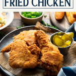 Side shot of a plate of buttermilk fried chicken recipe with text title box at top