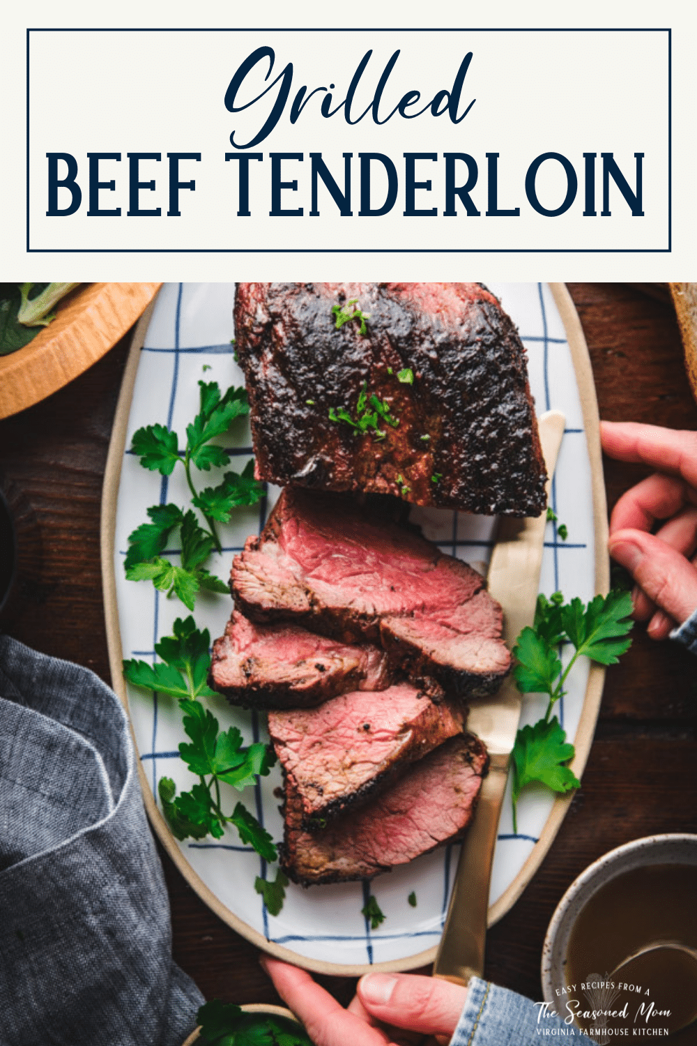 Overhead shot of hands holding a plate of grilled beef tenderloin with text title box at top