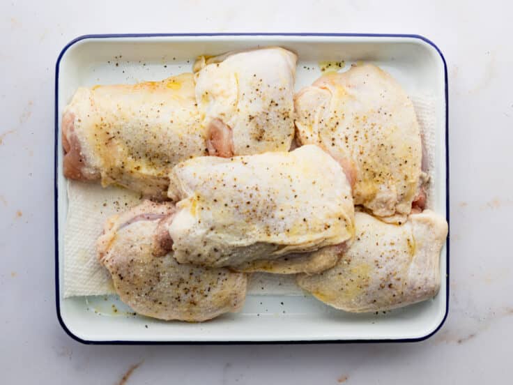 Platter of bone-in skin-on chicken thighs.