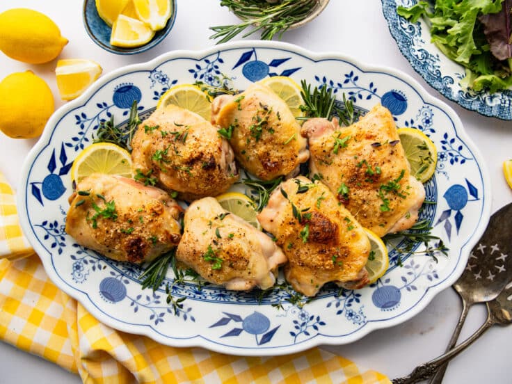 Horizontal overhead image of a blue and white platter full of crispy lemon roasted chicken.