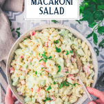 Overhead image of hands serving a bowl of old fashioned macaroni salad with text title overlay