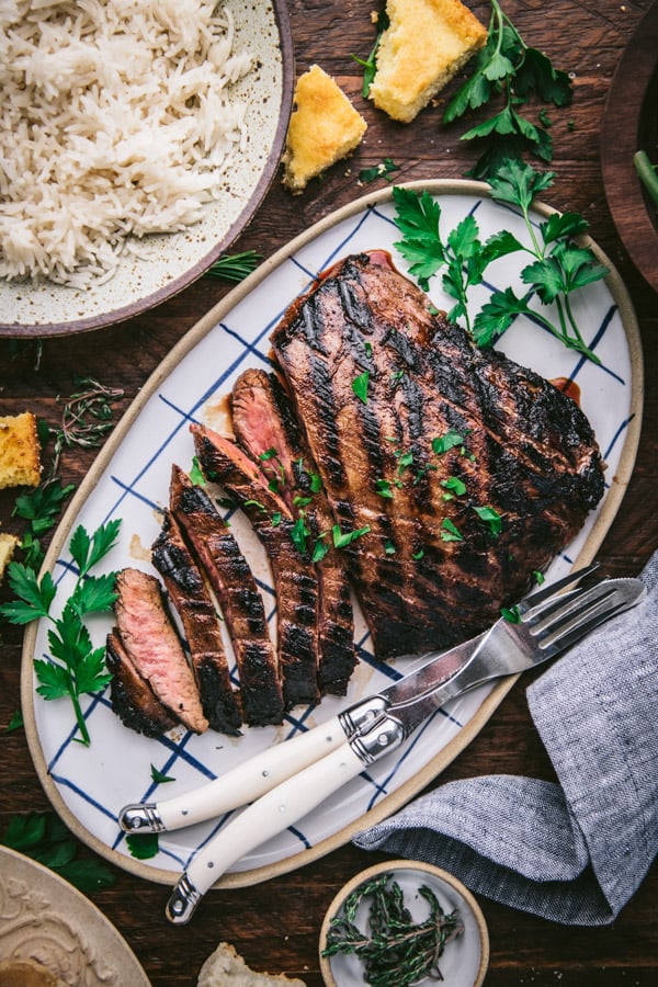 Overhead image of a marinated flank steak on a tray with a side of rice
