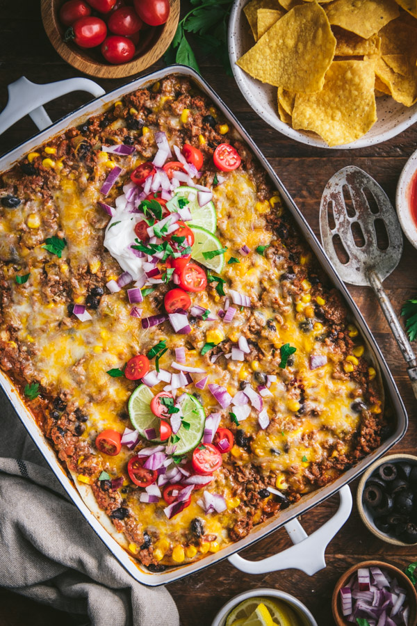 Overhead shot of the best mexican lasagna recipe with fresh toppings on the side