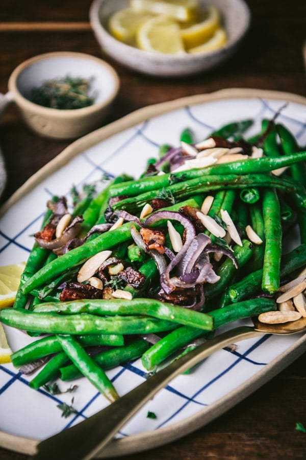 Close up side shot of the best roasted green beans recipe with bacon and a wooden table