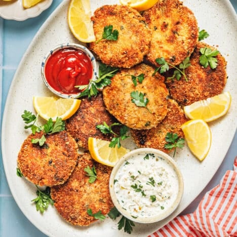 Square overhead shot of an easy salmon patties recipe served on a platter with cocktail sauce and tartar sauce.