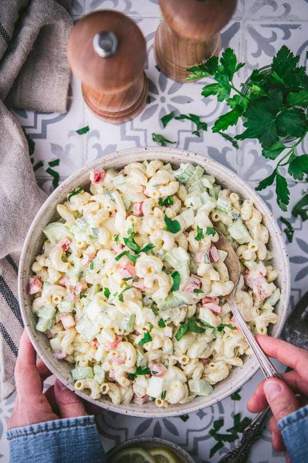 Overhead shot of hands serving macaroni salad with a big spoon