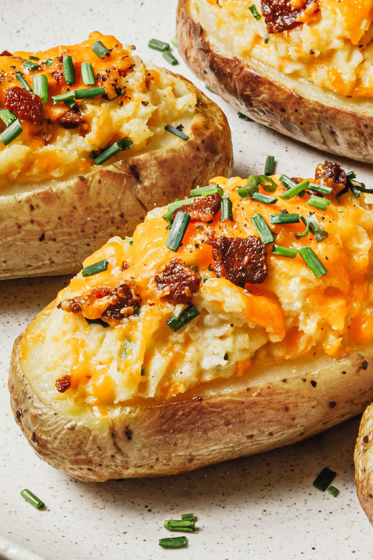 Close up side shot of twice baked potatoes on a serving tray.