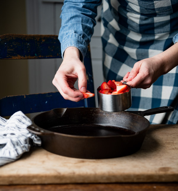 Arranging strawberries in the bottom of a cast iron skillet