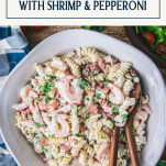 Close overhead image of a bowl of cold pasta salad with chicken shrimp and pepperoni and a text title box at top