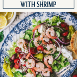 Overhead image of a plate of greek salad with shrimp and text title box at top
