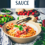 Side shot of a bowl of pasta pomodoro sauce on a table with text title overlay