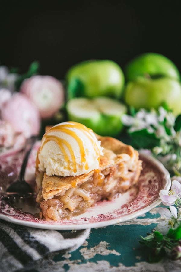 Close up front shot of a slice of easy apple pie with vanilla ice cream on top and caramel sauce