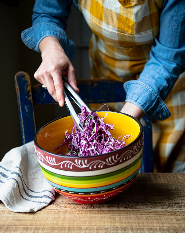 Tossing together fish taco slaw in a bowl