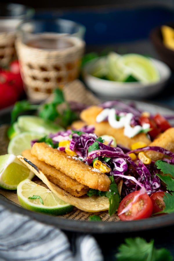 Side shot of crispy fried fish tacos with coleslaw on a plate