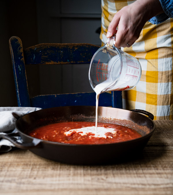 Adding cream to tomato sauce in a skillet