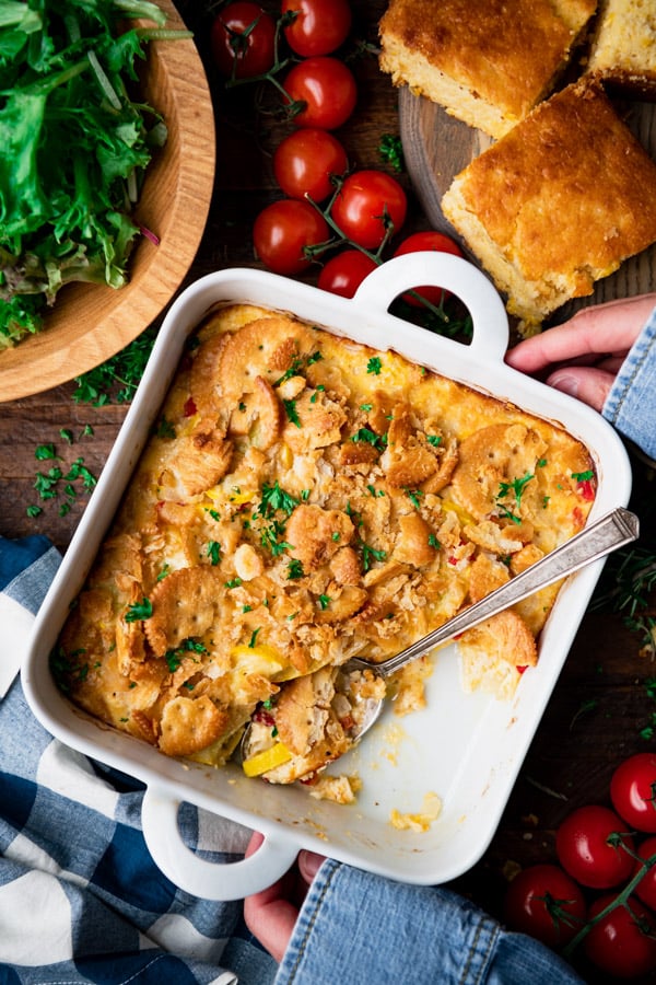 Overhead image of hands holding summer squash casserole