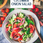 Overhead image of hands holding a white bowl full of cucumber tomato onion salad with text title overlay