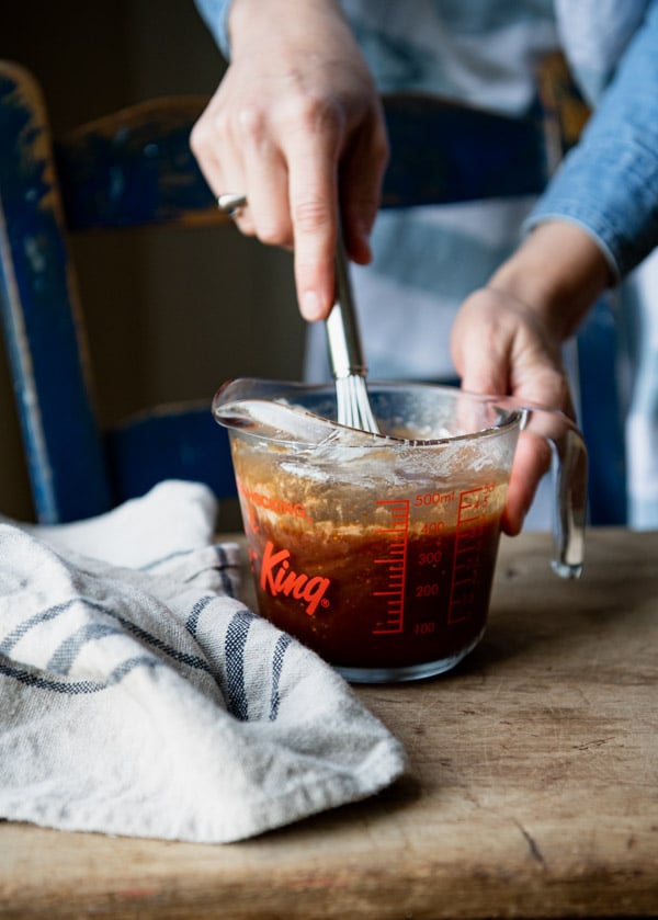 Whisking together sesame chicken sauce in a glass measuring cup