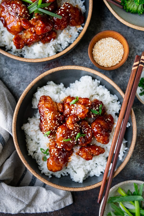 Close overhead shot of sesame chicken in a bowl over rice
