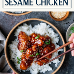 Overhead shot of hands using chopsticks to eat sesame chicken with text title box at top