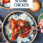 Hands eating sesame chicken with chopsticks and text title overlay