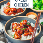 Side shot of a bowl of sesame chicken with white rice and text title overlay