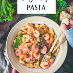 Overhead image of a bowl of shrimp and pasta sausage with gold utensils and text title overlay