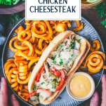 Hands holding a plate of philly chicken cheesesteak and fries with text title overlay
