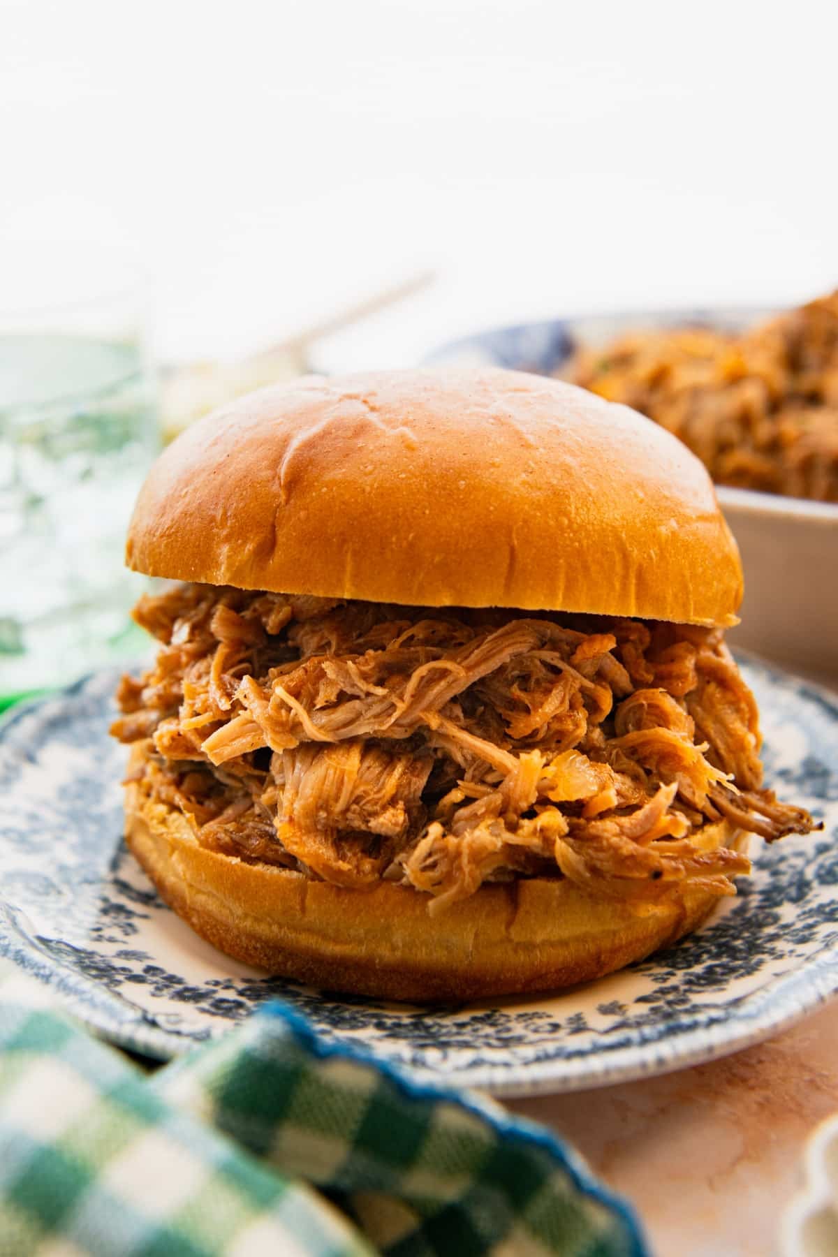 Side shot of an apricot pulled pork sandwich on a plate.