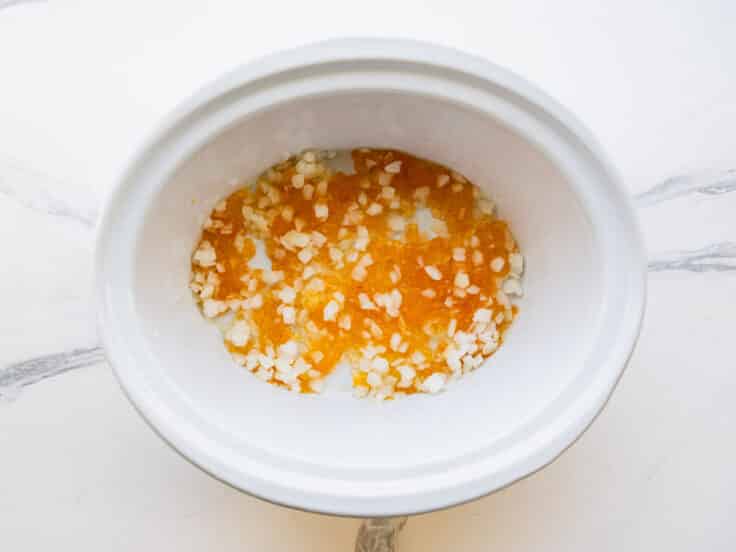 Apricot preserves and onion in the bottom of a slow cooker.