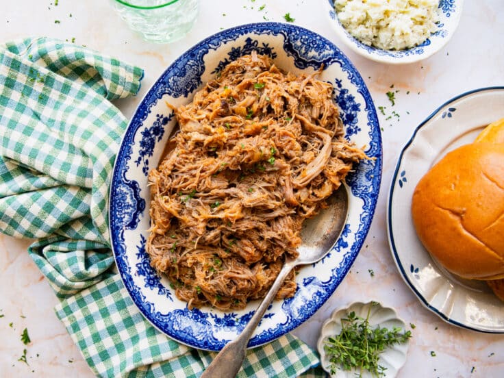 Horizontal overhead shot of shredded apricot pulled pork in a blue and white serving bowl.
