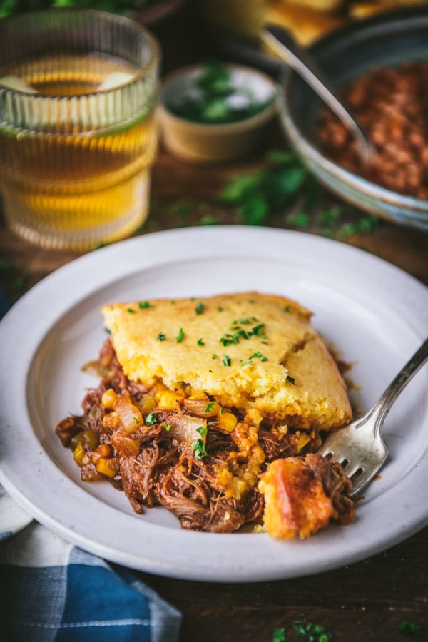 Close up side shot of leftover pulled pork casserole with cornbread topping on a white plate
