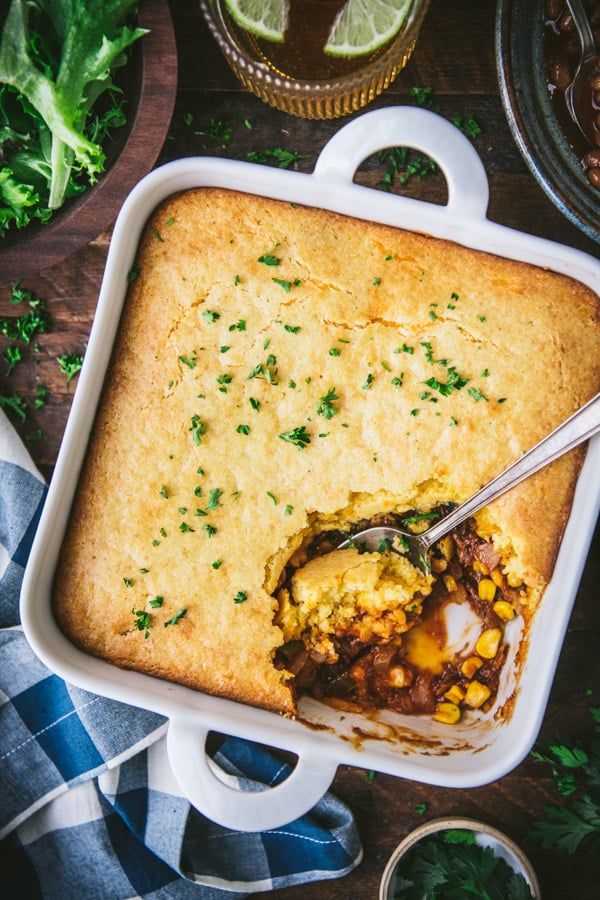 Close overhead image of a white dish full of pulled pork casserole with cornbread topping