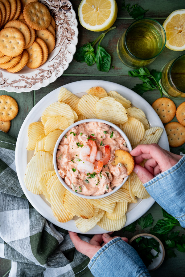 Overhead image of a hand dipping a Ritz cracker in old fashioned Southern shrimp dip recipe