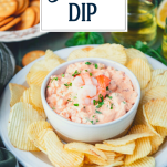 Side shot of a platter of shrimp dip with potato chips and text title overlay