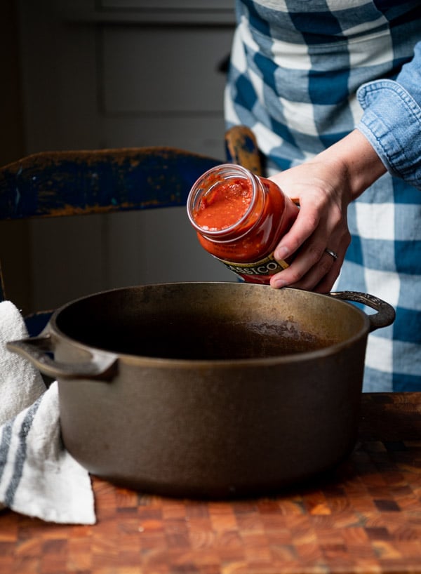 Pouring marinara sauce into a pot